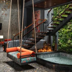 A custom swing suspended over a tranquil water body in the Utopia residence. This feature, set against a dramatic stone wall and adjacent to the vertical garden, creates a multi-sensory experience that is both playful and deeply calming.