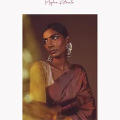 A portrait from a campaign shoot where light and shadow do the talking. We styled this look with a simple, elegant saree and striking silver jhumkas to create a feeling of quiet strength and grace. The warm, directional light highlights the model's features and the texture of the fabric.