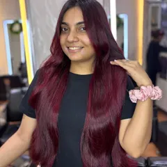 A happy client showing off her new cherry red hair. This bold color looks fantastic and is guaranteed to turn heads and steal hearts.