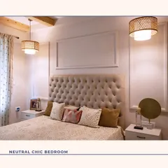 A perfect example of a neutral chic bedroom. The tall, tufted headboard in a soft beige fabric serves as the focal point, flanked by minimalist side tables and woven pendant lights that add texture and warmth to the serene space.