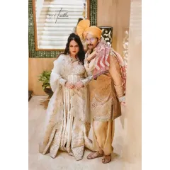 A classic couple portrait showcasing their coordinated outfits and regal presence. The bride and groom stand together, exuding elegance and a deep connection.