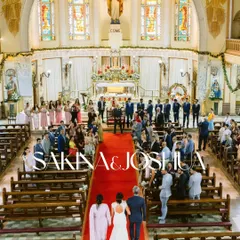 A wide shot capturing the grandeur of a Catholic wedding ceremony, with the bride walking down the aisle towards her groom, surrounded by family and friends in a beautiful church.