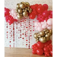 An elegant Valentine's Day or anniversary setup. This design uses a heart-string curtain with a red, pink, and gold balloon arch for a sophisticated and romantic feel.