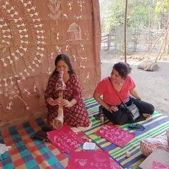 An instructor and student work side by side against a backdrop of authentic Warli wall art. This retreat offers a rare opportunity to learn in a truly immersive setting.