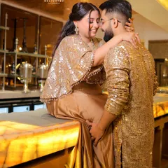 A stylish and romantic shot of the couple at their engagement party, seated on a bar counter. The warm lighting and their close embrace create a chic, modern vibe.