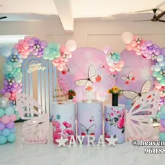An enchanting butterfly-themed party with a pastel rainbow balloon arrangement. This setup includes large, freestanding butterfly wing props, custom-printed plinths, and a personalized backdrop, creating a magical atmosphere.