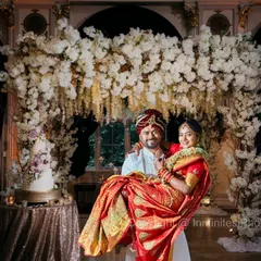 A classic portrait with a touch of grandeur. The groom holding his bride, framed by a stunning floral mandap, creates a timeless and romantic wedding photograph.