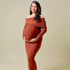 A classic, full-length portrait in a form-fitting brown dress. The clean, solid background and simple pose create a timeless and elegant look.
