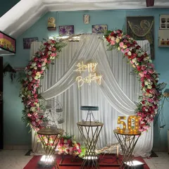 Celebrating a major milestone like a 50th birthday calls for an elegant touch. Here, I designed a beautiful circular backdrop framed with a lush garland of fresh flowers, complemented by a custom neon sign and large, illuminated numbers to mark the special occasion.