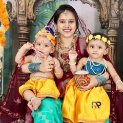Double the cuteness in this Radha-Krishna themed shoot. A mother holds her two little ones, both dressed in adorable traditional costumes, creating a vibrant and memorable portrait.