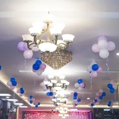 A view of the ceiling decor in the wedding hall, with elegant chandeliers and clusters of balloons adding to the festive atmosphere.