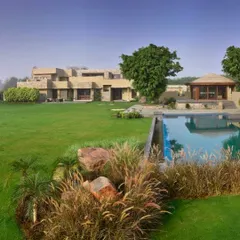 An expansive view of the C Farm landscape, showing the relationship between the main house, the infinity pool, and the garden pavilion. The design uses large, open lawns and carefully placed foliage to create a sense of scale and serenity.