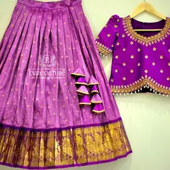 A royal purple pattu pavadai set. The pleated silk skirt has a wide gold zari border, and the matching blouse is adorned with delicate pearl and gold butti embroidery.