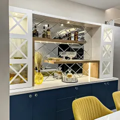 An elegant bar and crockery unit with a diamond-patterned mirror backsplash. The design includes glass-front cabinets, wine racks, and deep blue base cabinets for a sophisticated touch.