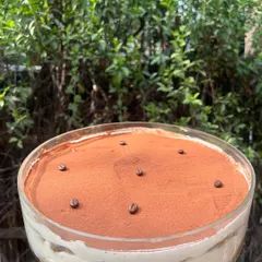 My classic Tiramisu in a large glass bowl, dusted with cocoa and topped with coffee beans. It’s a timeless Italian dessert that I make with authentic ingredients.