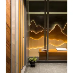 The entrance to the showroom, where a curved wooden wall guides visitors inside. The view is framed to immediately draw attention to the back-lit, mountain-inspired veneer art piece.