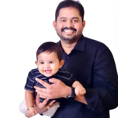 A proud father holds his smiling baby boy. This clean, classic studio portrait against a white background puts all the focus on their happy expressions and the bond they share.