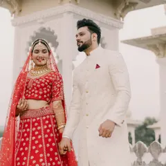 A candid moment between the bride and groom. Our groom's custom-fit ivory sherwani, with its subtle texture and clean lines, adds to the timeless elegance of their wedding day.