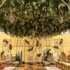 I created an enchanted forest mandap with a ceiling of cascading greenery and pink roses. The design includes delicate chandeliers nestled within the foliage, casting a romantic glow over the wedding ceremony.