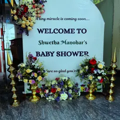 An elegant welcome sign for a baby shower. The board is decorated with an arch of fresh flowers, creating a beautiful and inviting entrance for guests.