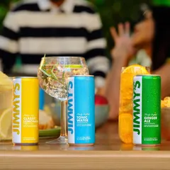 A lively party scene featuring Jimmy's cocktail mixers. The focus is on the products at the center of a social gathering, with blurred figures in the background creating a sense of fun and camaraderie.