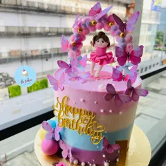 A beautiful ballerina and butterfly cake for a first birthday. This striped pastel cake is adorned with a dancing ballerina topper under an arch of butterflies.