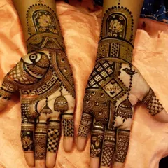 This design combines several auspicious elements for Karwachauth, including jhumka motifs, swastikas for good fortune, and a space to write a name. The intricate check patterns and floral work make it a traditional yet personalized choice.