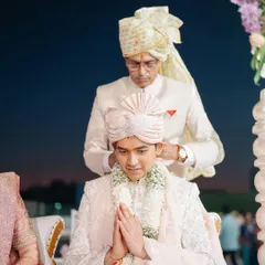 A father adjusts his son's turban, a quiet moment of blessing and pride before the wedding ceremony begins.