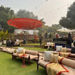 An overview of a Haldi and Mehendi setup on our lawns, featuring low diwan-style seating and our signature red canopy over the bar.