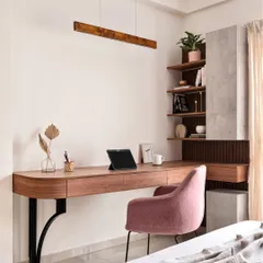 This elegant study nook features a floating wooden desk with a beautiful curved edge, supported by stylish black metal brackets. The combination of a pink upholstered chair and concrete-finish shelving creates a modern and sophisticated workspace.