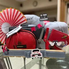 A vibrant red and grey themed hamper for a newlywed couple, celebrating "The Magic of New Beginnings". This gift includes personalized caps, matching pouches, and travel accessories for their journey ahead.