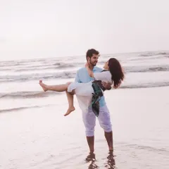 A classic romantic pose, with him carrying her in the shallow waves. This pre-wedding beach photo feels both heroic and tender.