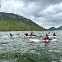 A group of kayakers spreads out across the water at Vani Vilas Sagar, enjoying the freedom and scenery. You can see the windmills on the surrounding hills, a unique feature of this location.