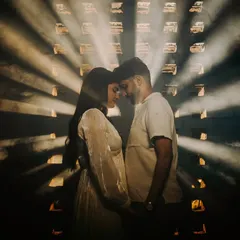 A dramatic silhouette of the couple, their foreheads touching, as beams of light cut through the smoky darkness. This is a powerful, moody, and cinematic shot that focuses purely on their connection.