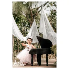 A little ballerina at her piano. Dressed in a beautiful pink tutu, this little girl is ready to dance and play in a dreamy outdoor setting.