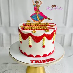 A stunning cake celebrating the grace of Indian classical dance. This design is inspired by Bharatanatyam, with intricate red and gold details and a beautiful dancer topper for Trisha's birthday.