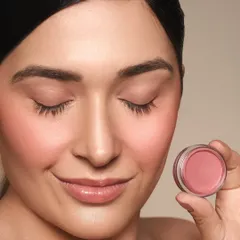 A close-up beauty shot demonstrating a soft, rosy blush from CS Essentials. The makeup is minimal to keep the focus on the product's color and texture on the skin.