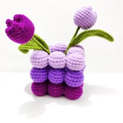 This adorable crochet tulip pot features shades of purple and is perfect for your workspace or any empty corner. The pot itself is made of soft, crocheted bobbles, adding a unique texture to the decor.