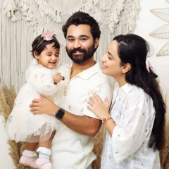 The joy of a young family. This candid shot captures the loving gaze between parents as they hold their smiling baby girl, a perfect example of a lifestyle family portrait.
