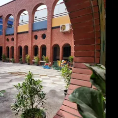 A view of the school courtyard through a brick archway, creating a beautiful frame for the playful and colorful environment within. The design uses classic architectural elements to create a sense of rhythm and order.