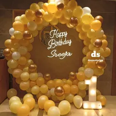 An elegant ring decoration for a first birthday, using a warm palette of yellow, white, and chrome gold balloons. The setup is personalized with a custom neon name sign and a light-up number '1'.