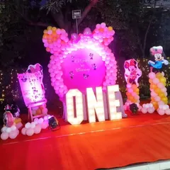 The same Minnie Mouse party setup illuminated at night. The marquee letters and spotlights create a magical and festive glow for evening celebrations.