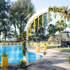 A chic poolside Haldi setup. The white floral arch with hanging marigolds beautifully frames the pool, creating a fresh and stylish ambiance for a modern Haldi ceremony.