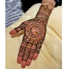 This Karwachauth design features a central mandala with a depiction of a woman looking through a sieve at the moon. The fingers are adorned with names, making it a personalized piece.