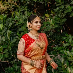 A stunning bride in her red and gold wedding saree. The makeup features classic kohl-rimmed eyes and a matte red lip, a signature look for South Indian weddings.
