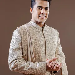 This golden-beige sherwani is a study in intricate craftsmanship, featuring dense, traditional embroidery. It is an ideal choice for the groom seeking a classic, opulent look for his wedding ceremony.
