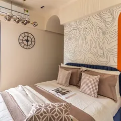 A full view of this imaginative kids' room, showing the bed with its unique topographic map wallpaper, a large wall clock, and a balcony that lets in plenty of natural light.