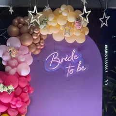 A close-up of the 'Bride to be' neon sign and the pastel-toned balloon garland from the terrace party setup.