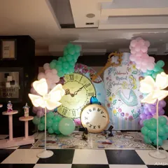 This 'Mystical Garden' version of the Alice in Wonderland theme featured a beautiful illustrated backdrop, giant clocks, and glowing flower lights. The checkerboard floor mat tied the whole whimsical scene together.