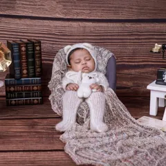 A vintage-themed setup featuring a baby in a knit outfit, surrounded by old books, a gramophone, and a rotary phone. This creates a charming, nostalgic scene.